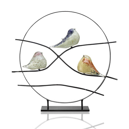 Circular sculpture with three colorful, glass birds on wire branches.