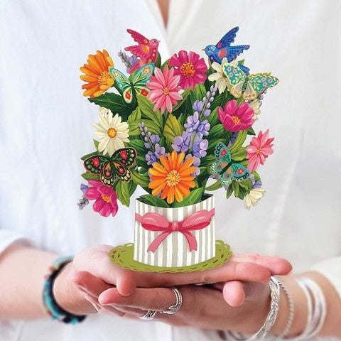 Hands holding a colorful paper bouquet with butterflies.