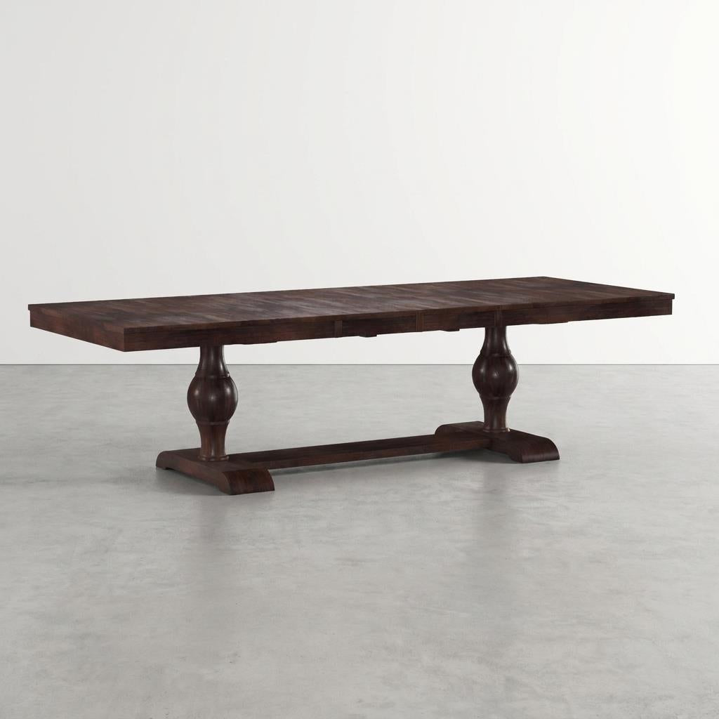 Dark wooden dining table with two pedestal legs on a light gray floor.