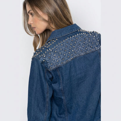 Woman in a studded denim jacket, viewed from the side.
