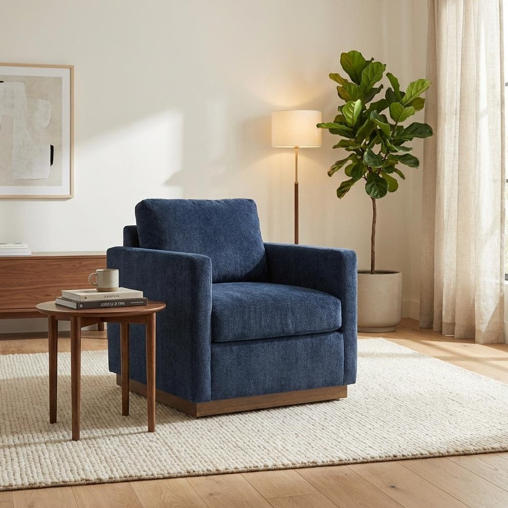 Cozy living room with blue armchair, table, lamp, and plant.