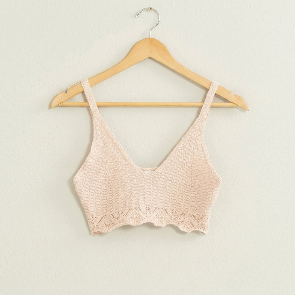 Beige crochet crop top on a wooden hanger.