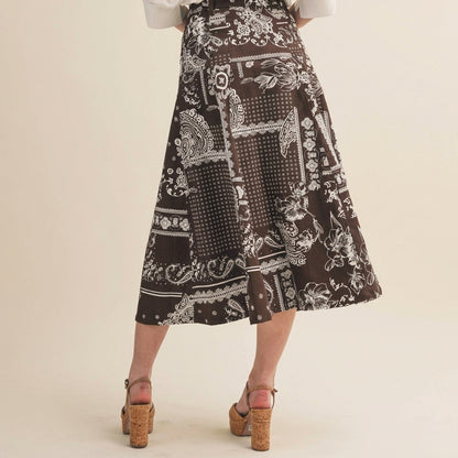 Brown patterned skirt, mid-length with floral designs, paired with heeled sandals.