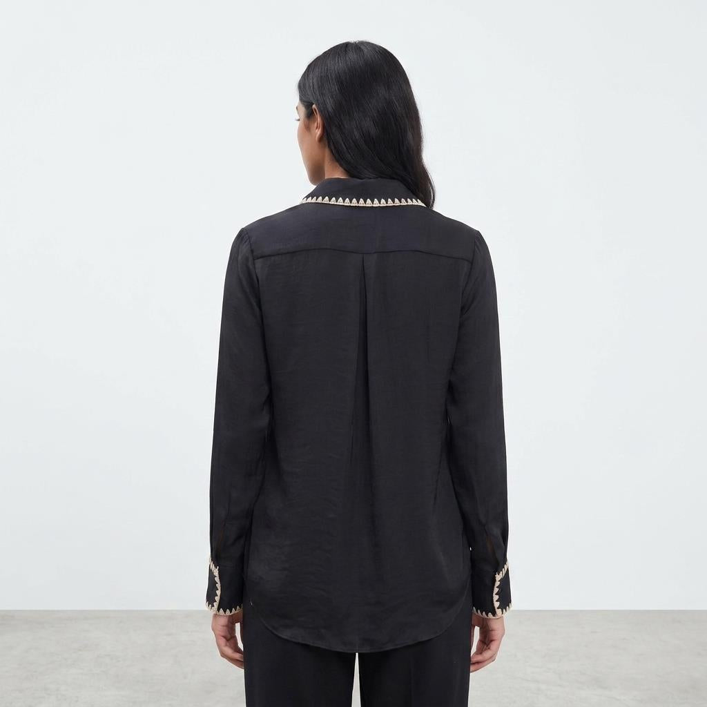 Person in black shirt with decorative collar, facing away.