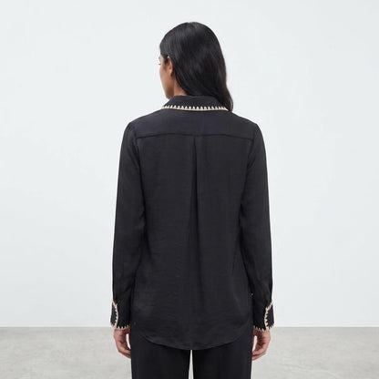 Person in black shirt with decorative collar, facing away.