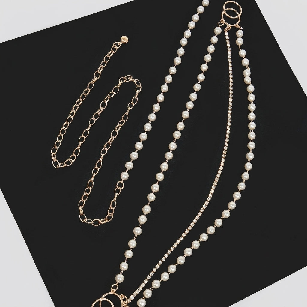 Gold chain and pearl necklace set on a black surface.