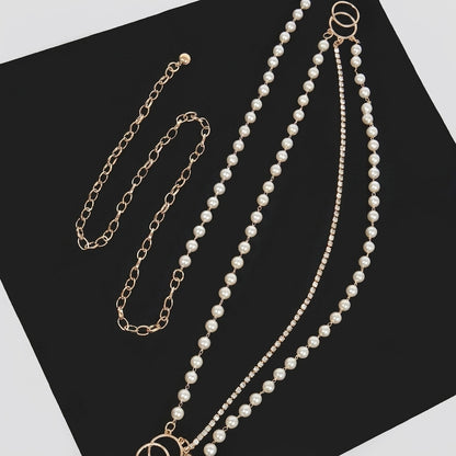 Gold chain and pearl necklace set on a black surface.