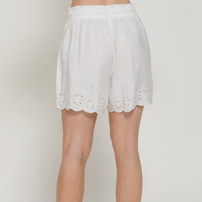 White shorts with floral cut-out hem design, worn by a person.