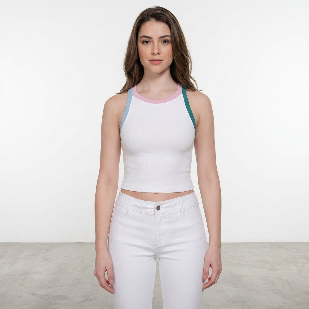 Woman in a white tank and pants, standing indoors on gray floor.