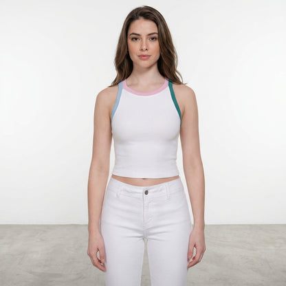 Woman in a white tank and pants, standing indoors on gray floor.