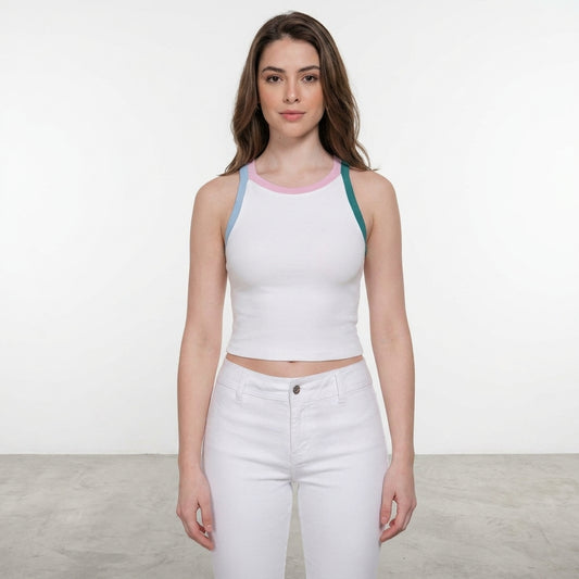 Woman in a white tank and pants, standing indoors on gray floor.