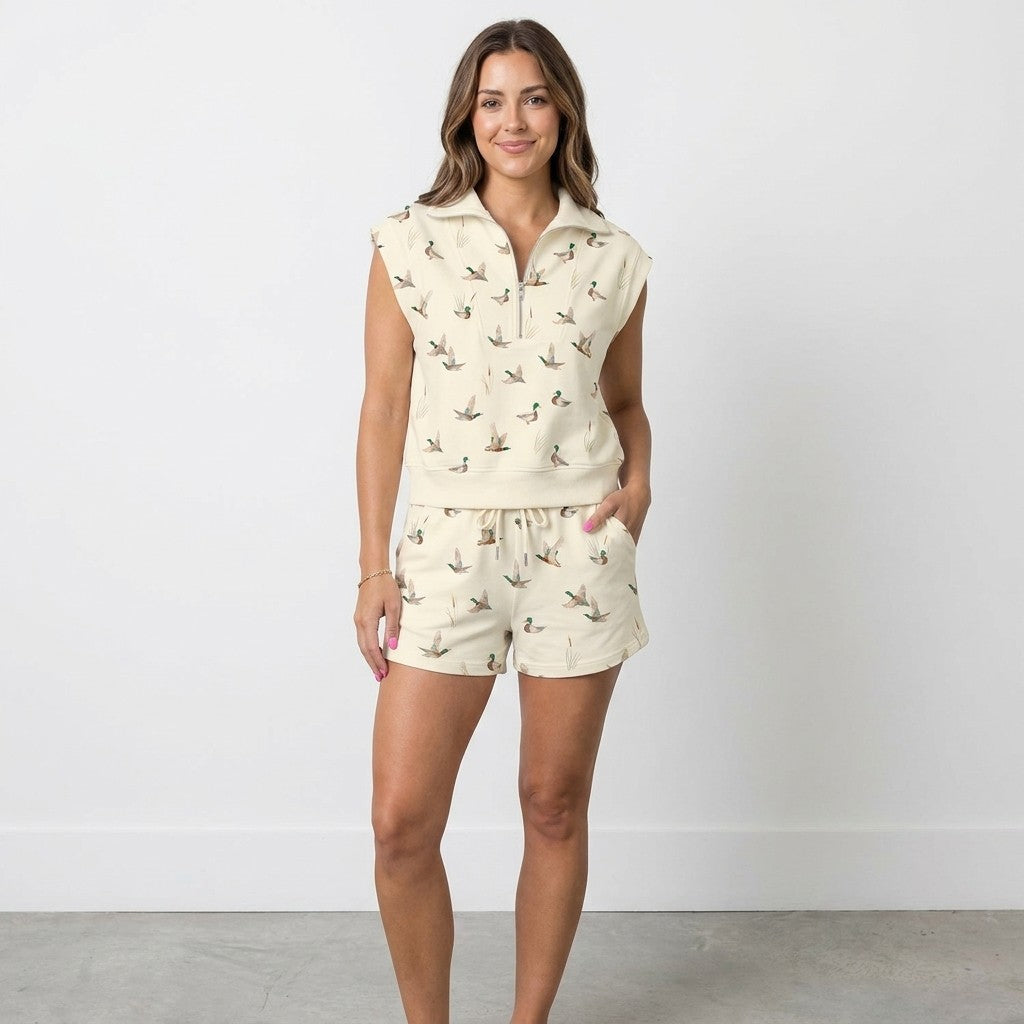 Smiling woman in duck-patterned shorts set against a plain background.