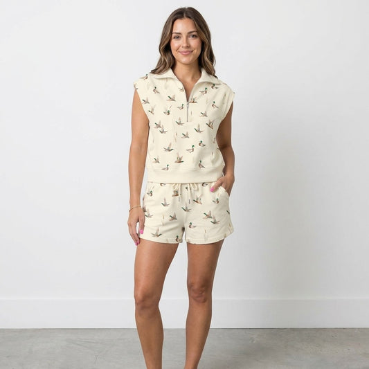 Smiling woman in duck-patterned shorts set against a plain background.