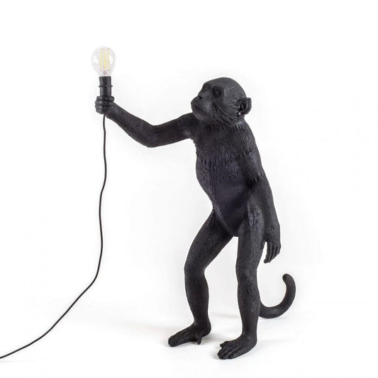 Black monkey lamp holding a light bulb.