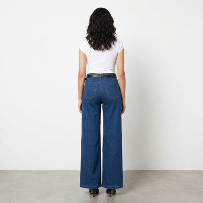 Person in white top and blue jeans, standing against a plain white background.