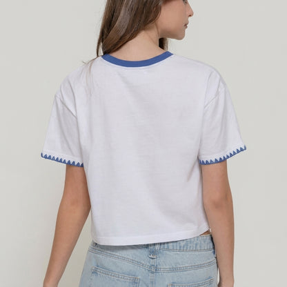 Person in a white and blue-trimmed shirt with light blue jeans, facing away.