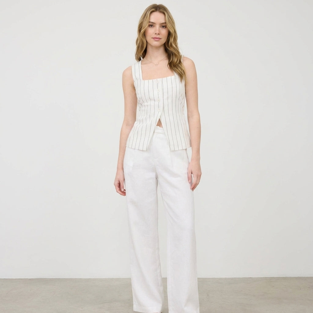 Woman in white-striped top and pants, standing against a plain background.