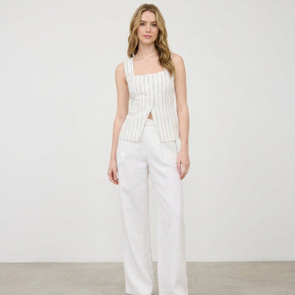 Woman in white-striped top and pants, standing against a plain background.