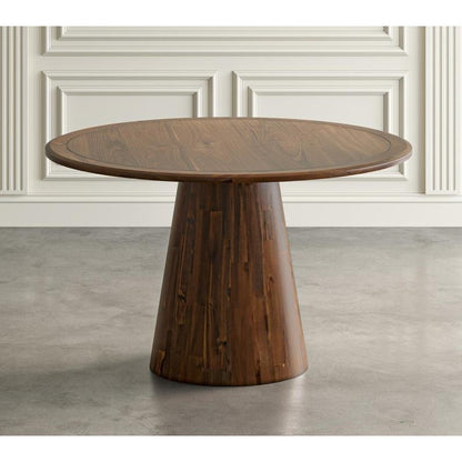 Round wooden table with a tapered base, set against a paneled wall.
