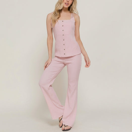 Woman in a pink button-up top and flared pants.