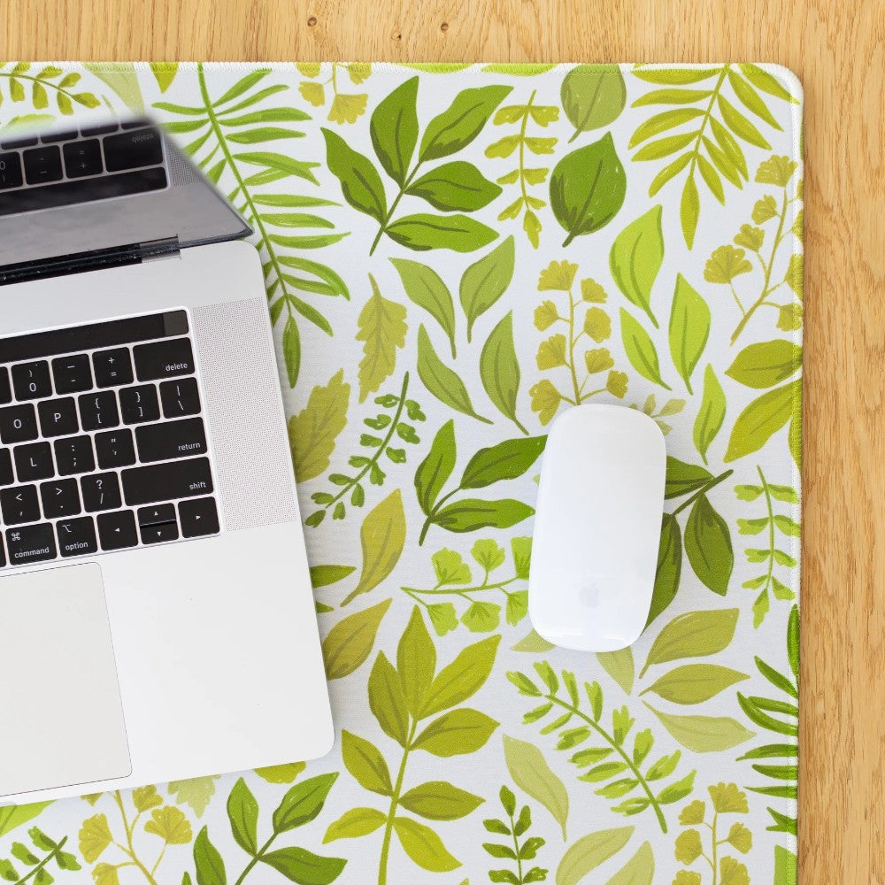 Laptop and mouse on leafy-patterned desk mat.