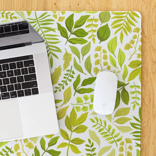Laptop and mouse on leafy-patterned desk mat.