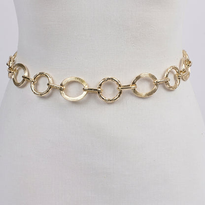 Gold chain belt on a white mannequin torso.