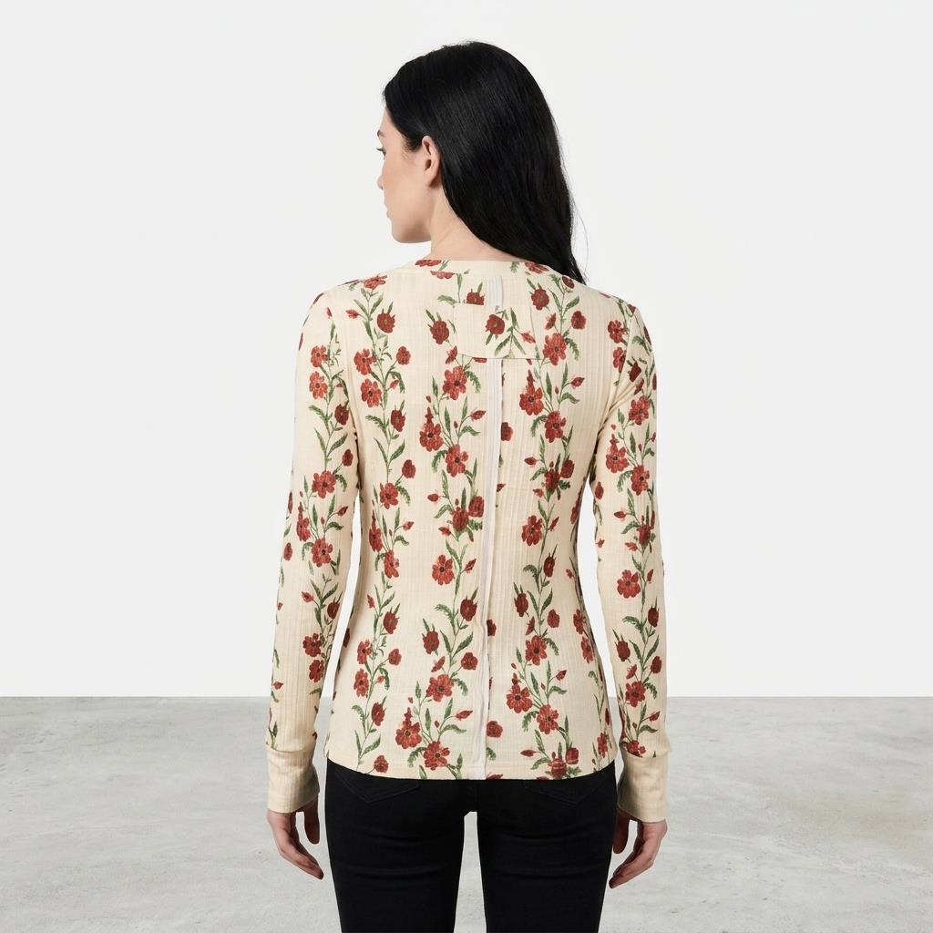 Woman in floral top and black pants, facing away in a minimalistic setting.
