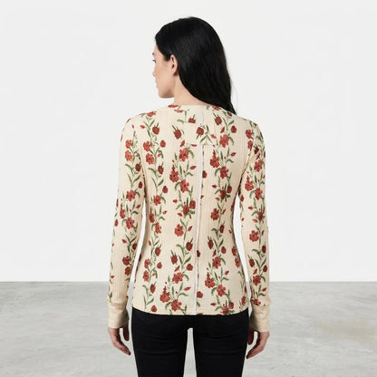 Woman in floral top and black pants, facing away in a minimalistic setting.