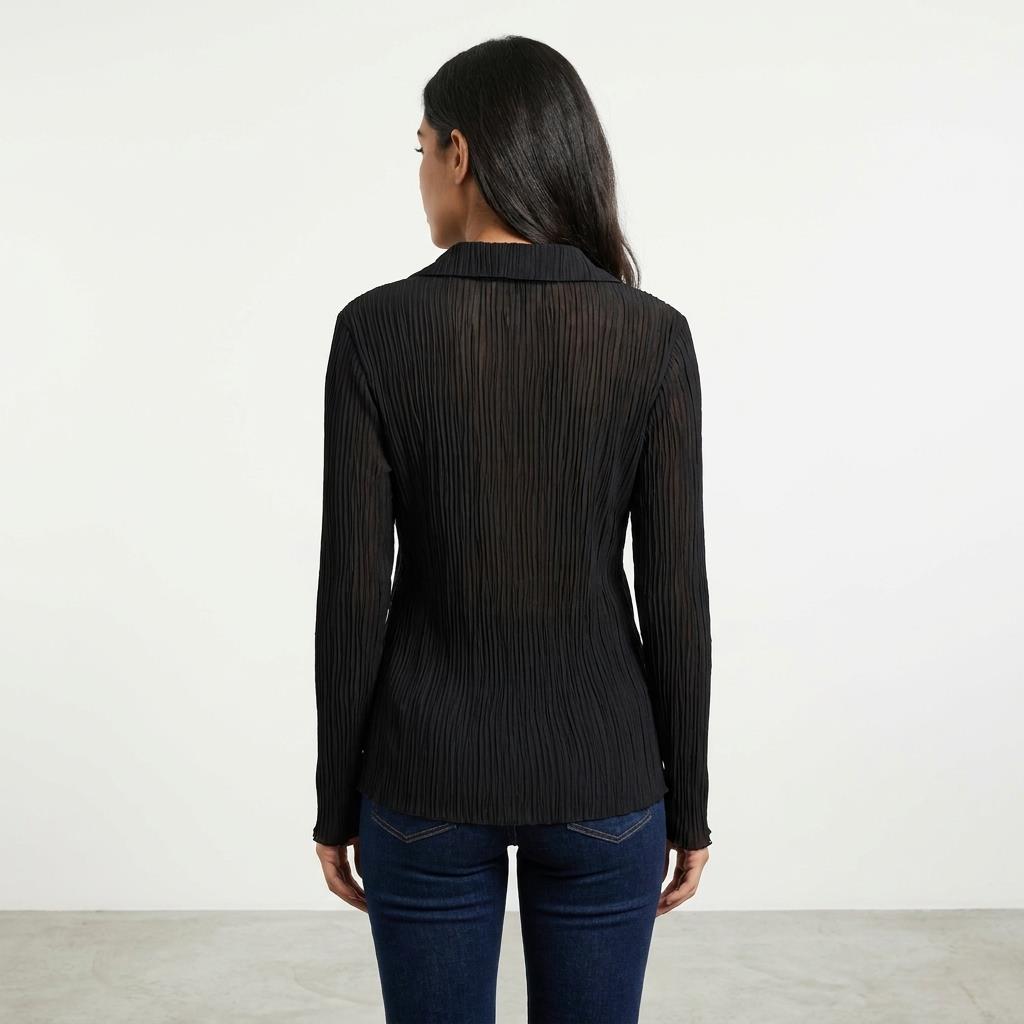 Woman in black sheer blouse and jeans, facing away.