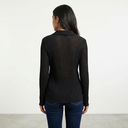 Woman in black sheer blouse and jeans, facing away.
