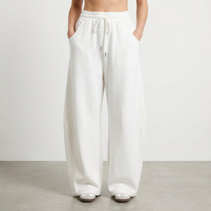 White wide-leg pants with drawstring and hands in pockets.