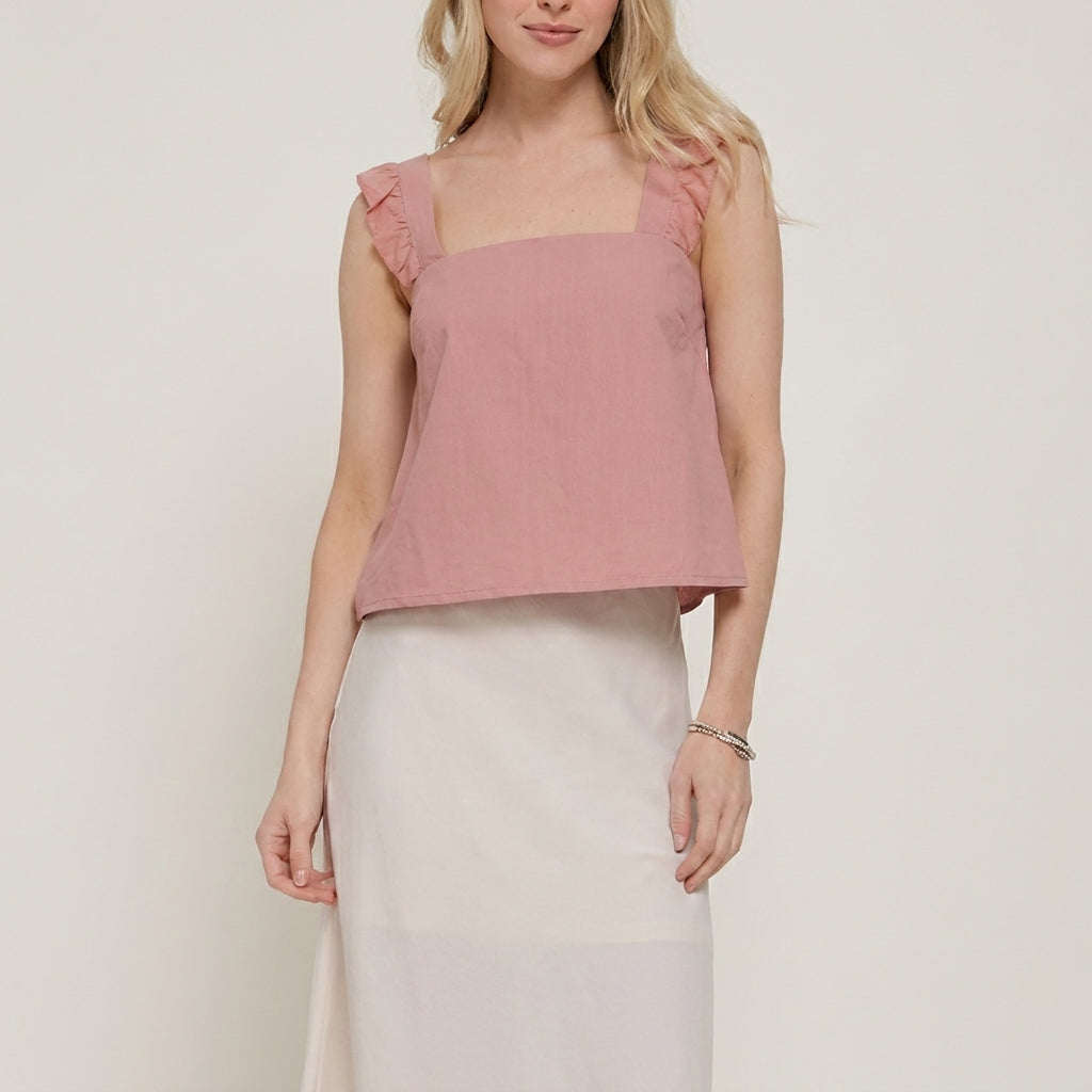Woman in pink sleeveless top and white skirt, simple and elegant attire.