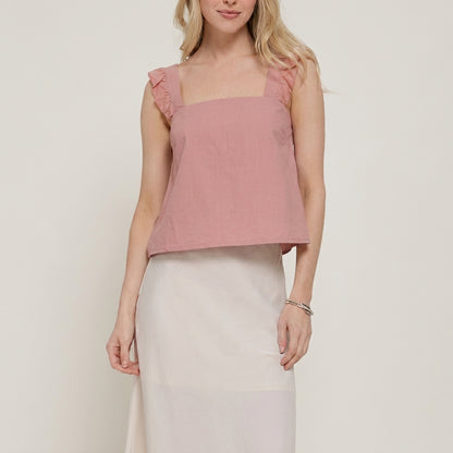 Woman in pink sleeveless top and white skirt, simple and elegant attire.