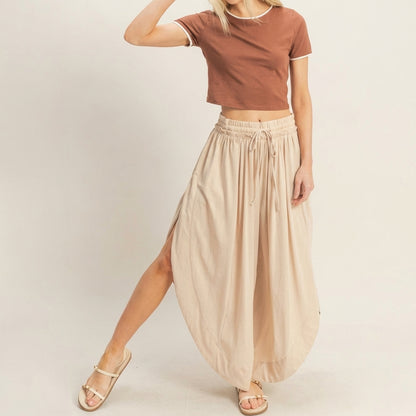 Woman in a brown crop top and beige wide-legged pants.