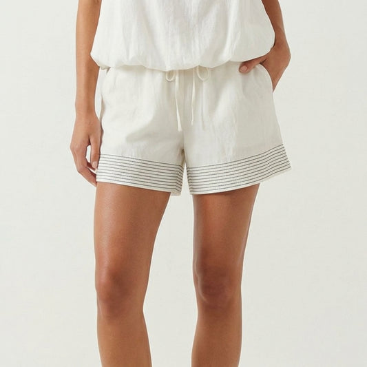 Woman in white shorts with striped trim.