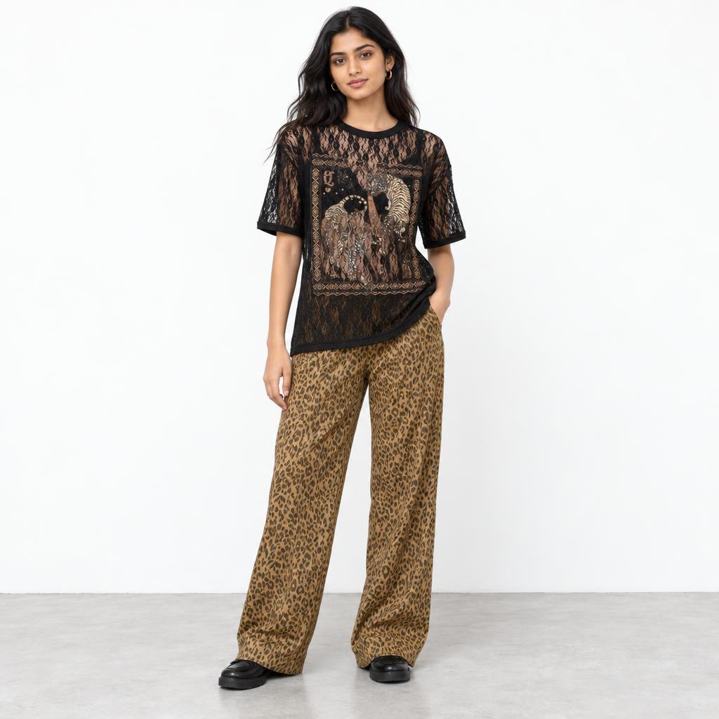 A woman models a black lace graphic top and leopard-print wide-leg pants against a white backdrop.