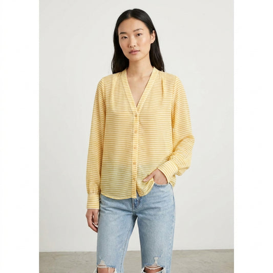 Person in a yellow striped shirt and jeans with hands in pockets.