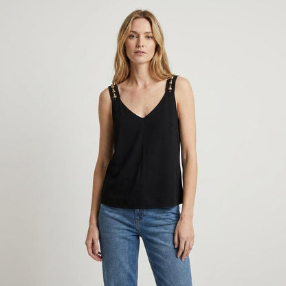 Person wearing a black sleeveless top and blue jeans against a plain background.