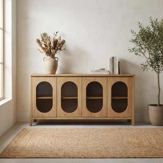 A warm minimalist room with a wooden sideboard, dried flowers, books, and a potted tree.