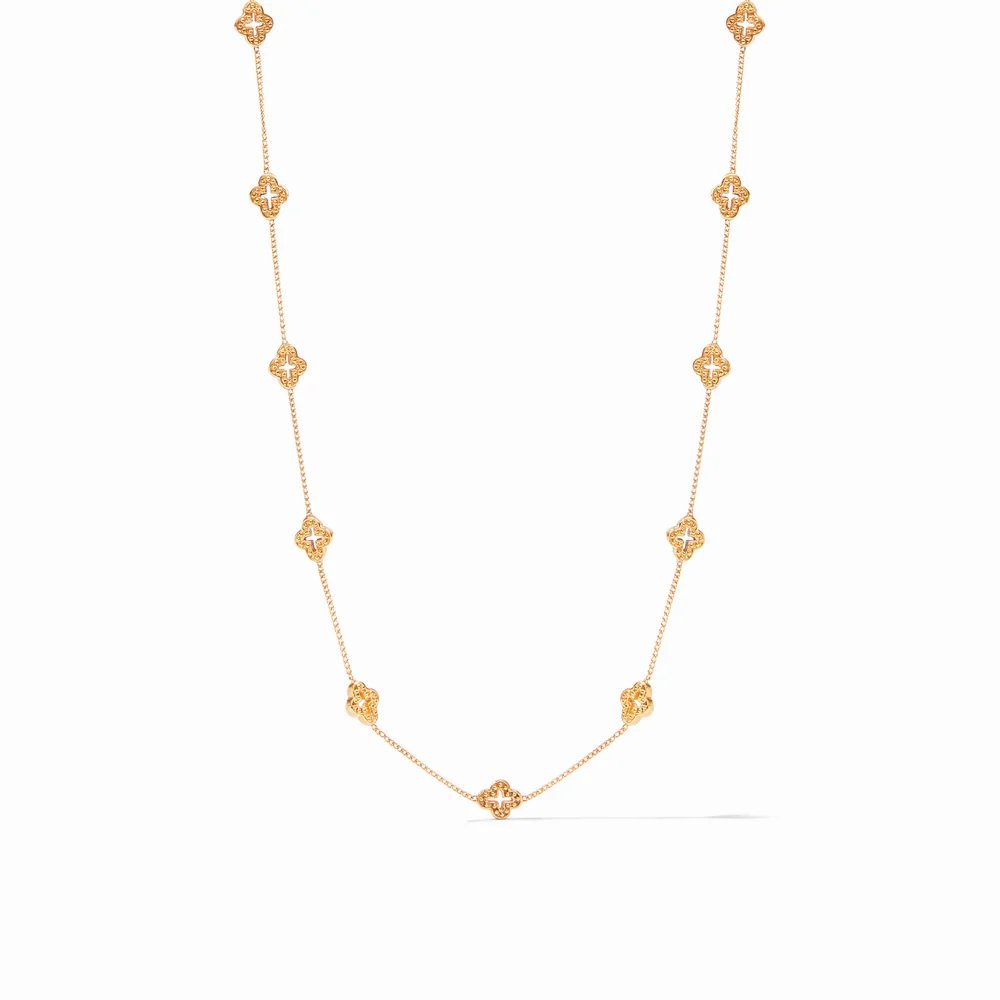 A delicate gold chain necklace featuring evenly spaced ornate clover-shaped charms.
