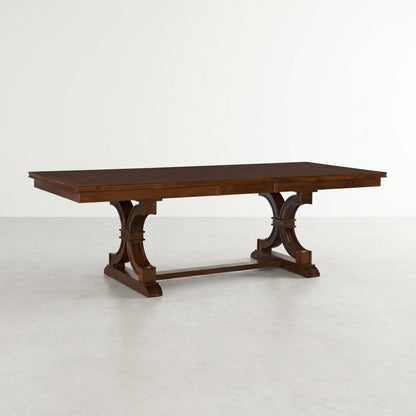 Wooden dining table with ornate trestle legs on a white background.