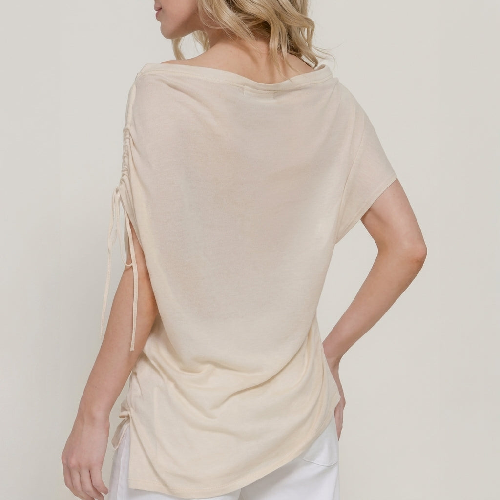 Woman in a cream top with draped back and side strings.