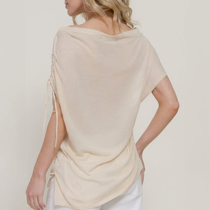 Woman in a cream top with draped back and side strings.