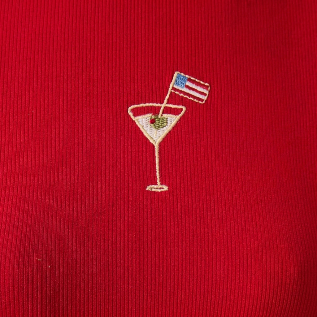 Embroidered cocktail glass with flag on red fabric.