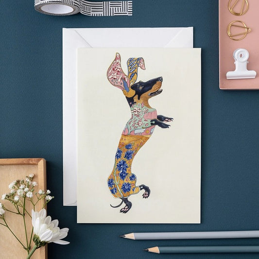 Colorful dachshund art on card, with flowers and stationery accents.
