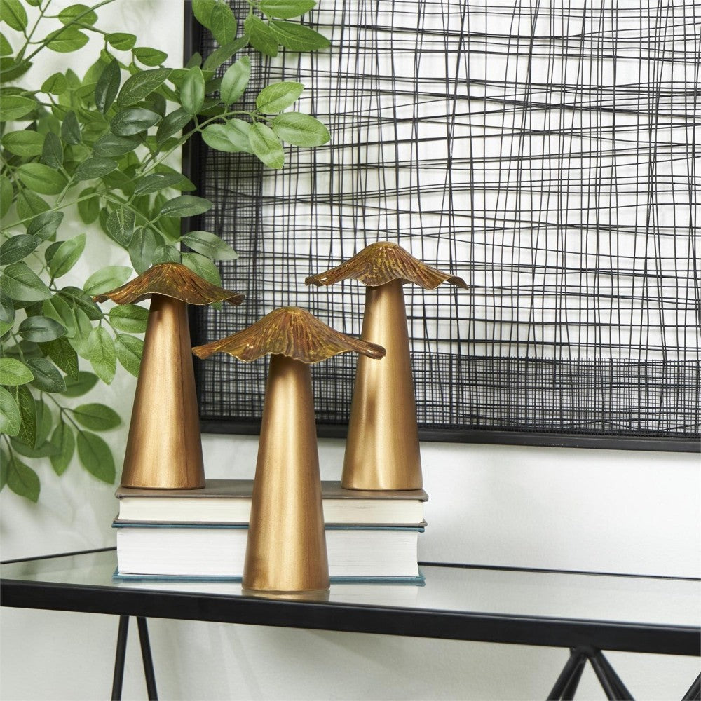 Three gold mushroom sculptures on books, leafy plant, and wire art backdrop.