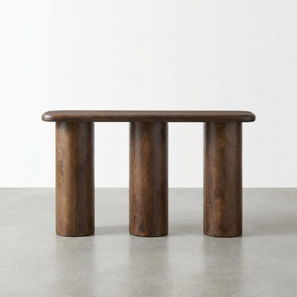 Wooden bench with three cylindrical legs on a gray floor.