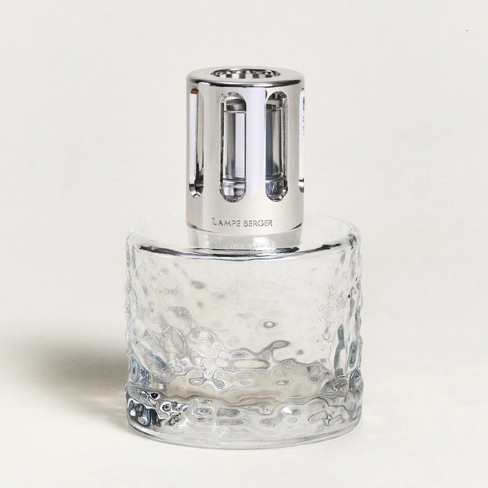 Glass fragrance lamp with silver top, plain background.