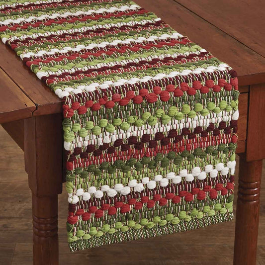 Colorful woven table runner with red, green, and white stripes on a wooden table.